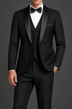 Man wearing a black three-piece tuxedo with shawl lapels against a charcoal-grey studio background